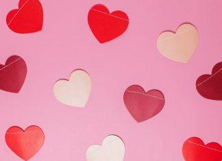 cut out hearts, which are different shades of pink and red, are shown against a light pink background.
