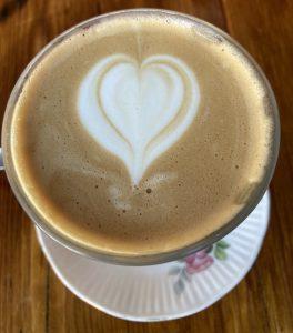 Looking down on a cup of coffee. A heart has been drawn in the milk foam on top.
